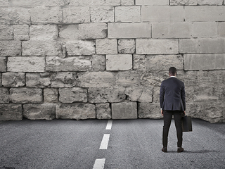 Anzugtraeger-vor-Mauer-157072263-AS-olly