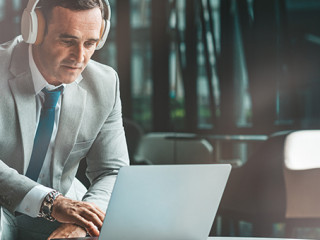 Anzugtraeger-Laptop-Kopfhoerer-284509719-AS-Adamov