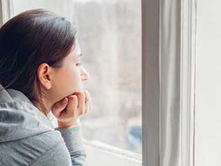 Frau-Fesnter-traurig-333936595-AS-maryviolet