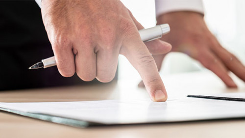 Hand-zeigt-auf-Papier-233885315-AS-Gajus