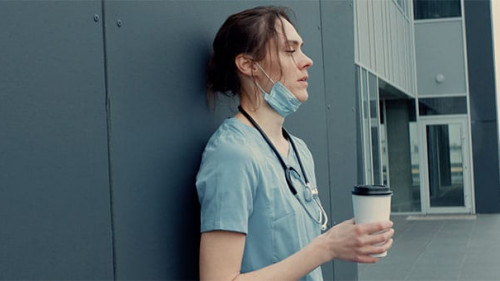 Krankenschwester-erschoepft-Kaffee-335506532-AS-daniilvolkov