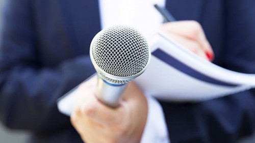 Anzugtraegerin-Mikrofon-283774771-AS-wellphoto