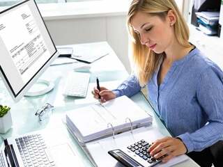 Young Businesswoman Calculating Bill In Office