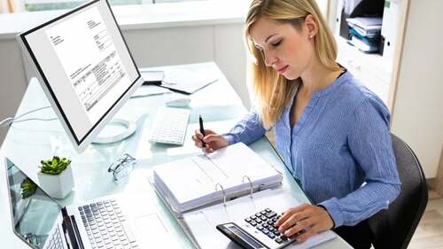 Young Businesswoman Calculating Bill In Office
