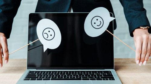 KYIV, UKRAINE - AUGUST 5, 2019: cropped view of woman holding sticks with emotions near laptop with blank screen