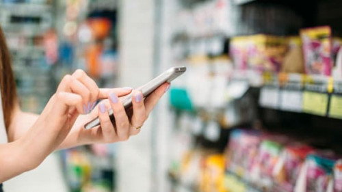 Female customer with phone in hand, food store