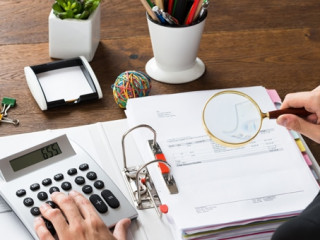 Businessman Inspecting Invoice At Desk