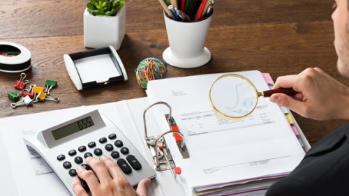 Businessman Inspecting Invoice At Desk