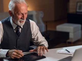 Happy mature editor using digitized pen while working on computer in his office.