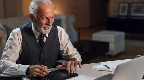 Happy mature editor using digitized pen while working on computer in his office.