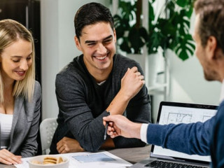 Young happy couple going through housing plans with real estate agent.