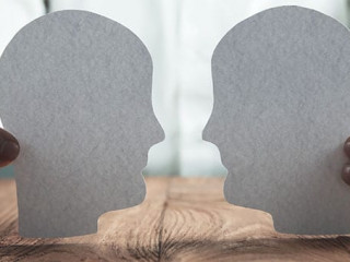 Businessman showing paper human heads on wooden desk. Business c