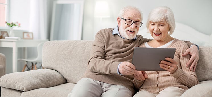 Joyful aged people looking at the tablet screen
