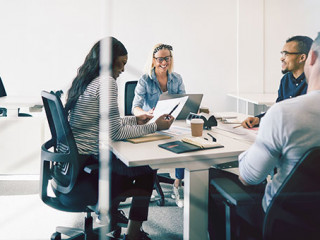 Smiling colleagues meeting together inside of a glass walled off