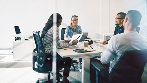 Smiling colleagues meeting together inside of a glass walled off