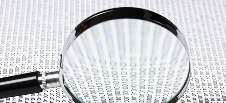 magnifying glass on a binary code