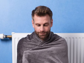 Man Sitting In Front Of Heater At Home