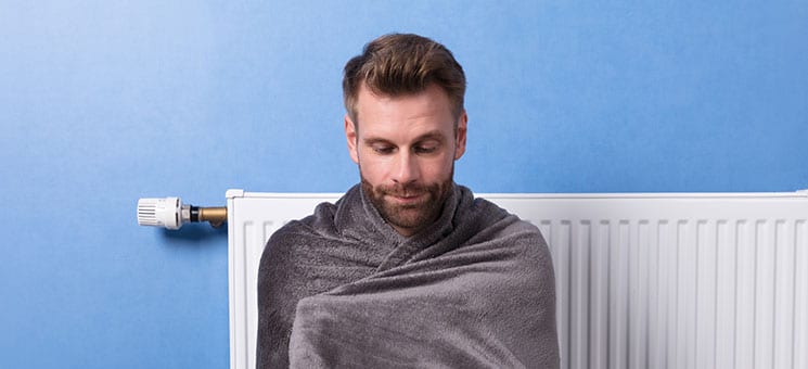 Man Sitting In Front Of Heater At Home