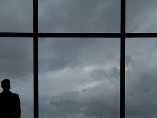 The man with suitcase standing near the big windows in the busin