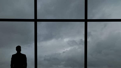 The man with suitcase standing near the big windows in the busin