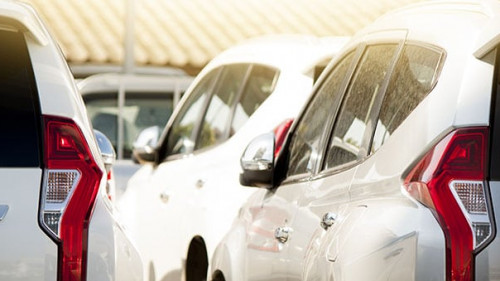 Many white car stop in parking lot outdoor on day.