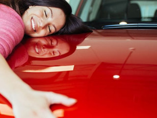 Happy beautiful young woman buying a new car at the car showroom