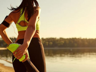 Young woman runner doing warm-up stretching her legs in a park.