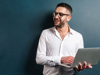 Happy man wearing glasses using laptop computer.