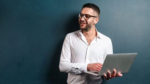 Happy man wearing glasses using laptop computer.
