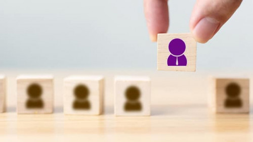 Hand of a businessman chooses a wooden cube block with icon peop