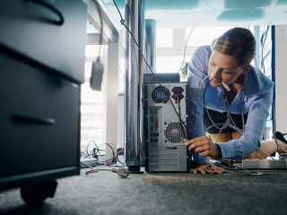 Young secretary connecting cables to pc in office