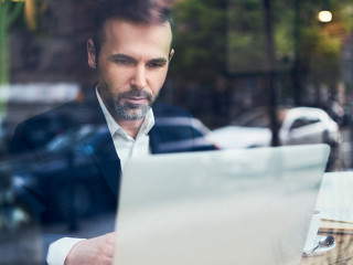 Handsome businessman working on laptop and sitting in cafe