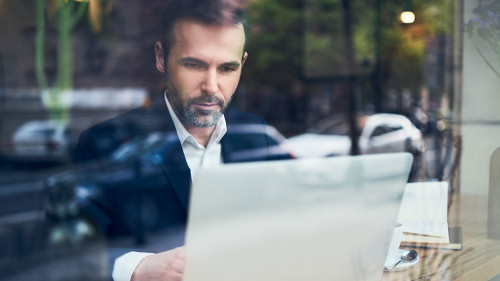 Handsome businessman working on laptop and sitting in cafe
