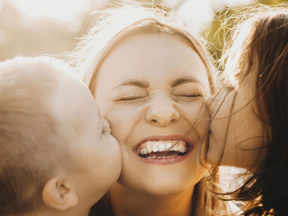 Close up portrait of lovely young mother laughing with closed ey