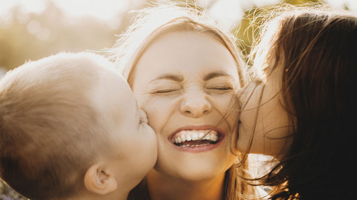 Close up portrait of lovely young mother laughing with closed ey