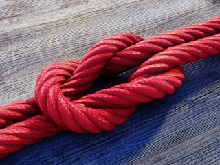 Kreuzknoten mit rotem Seil auf Holz