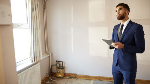 Male Realtor With Digital Tablet Carrying Out Valuation On Property For Renovation