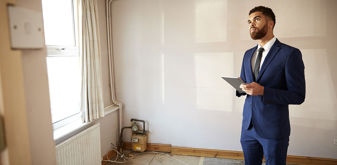 Male Realtor With Digital Tablet Carrying Out Valuation On Property For Renovation