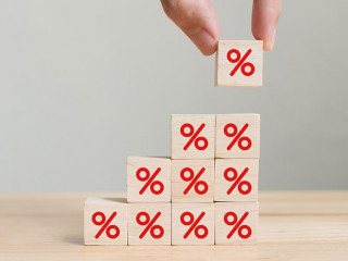 Interest rate financial and mortgage rates concept. Hand putting wood cube block increasing on top with icon percentage symbol upward direction