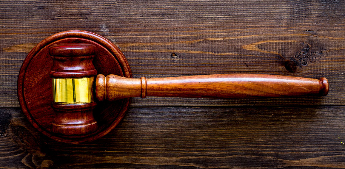 Car accident lawsuit concept. Two collided cars near judge gavel on dark wooden background top view copy space