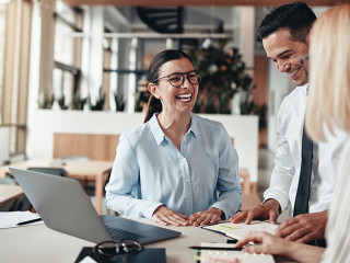 Businesspeople laughing while working at an office table