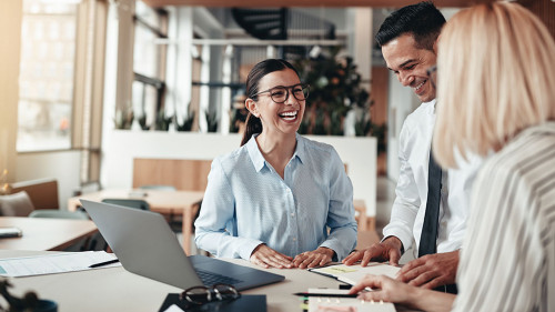 Businesspeople laughing while working at an office table
