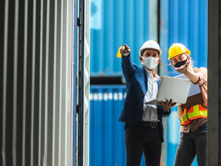 Business executives and engineers wear medical face masks. While inspecting industrial plants and container yard warehouses for international shipping businesses Concepts of import and export via airplanes and ships