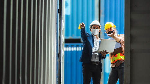 Business executives and engineers wear medical face masks. While inspecting industrial plants and container yard warehouses for international shipping businesses Concepts of import and export via airplanes and ships