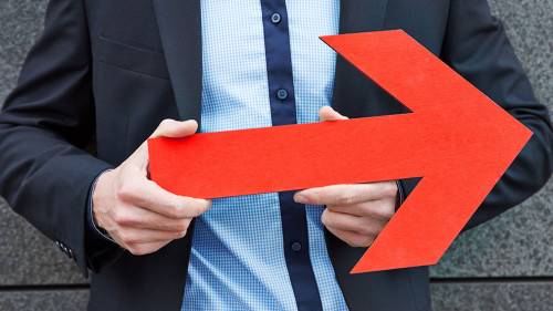 Mann hält roten Pfeil nach links