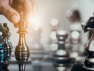 Businessman moving chess piece and think strategic to win game.