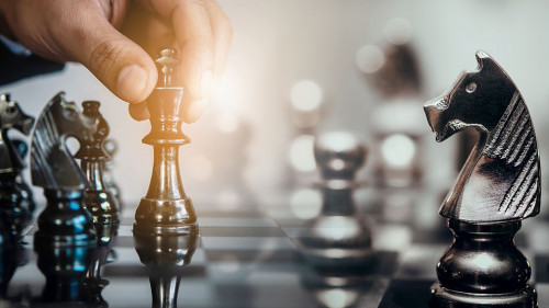 Businessman moving chess piece and think strategic to win game.