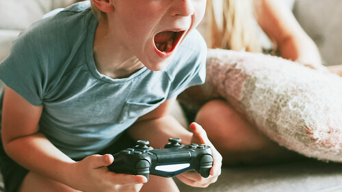 Young boy playing video game in living room
