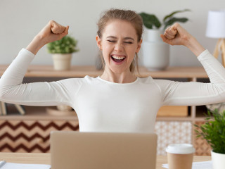 Excited woman feels happy sitting at the desk