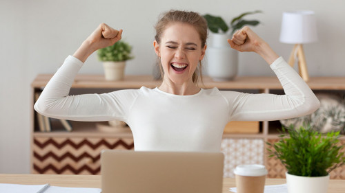 Excited woman feels happy sitting at the desk